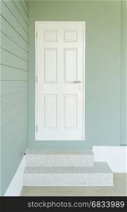 white door on the blue wall and two steps leading to entrance