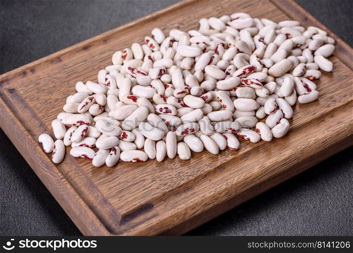 White dry raw beans on a dark concrete background. Cooking Healthy Food. White dry raw beans on a dark concrete background