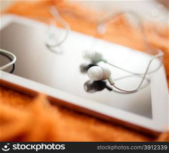 White earphones and tablet pc, close up photo, small dof