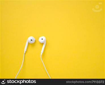 White earphones on yellow background. Earphones for listening to music and sound on portable devices.