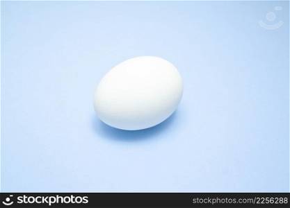 White easter egg on blue background in center. Design, visual art, minimalism.. White easter egg on blue background in center. Design, visual art, minimalism