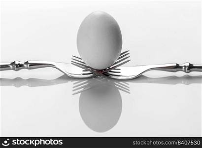 White egg on two table forks. Concept for advertising eggs as healthy food with different cooking variations. Concept for advertising eggs as healthy food with different cooking variations