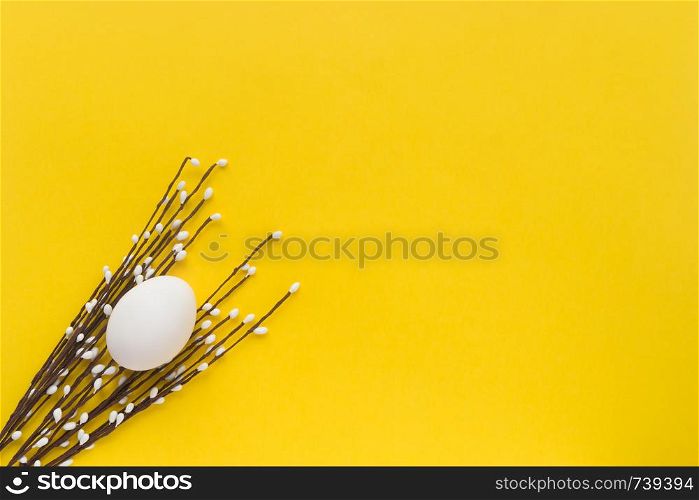 White Egg on yellow background with decor .Christian religious holiday. Happy Easter. Top view. Free space. Flatlay. White Egg with decorative twigs on yellow background .Christian religious holiday. Happy Easter. Top view. Free space. Flatlay