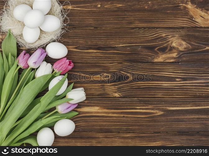 white eggs nest with bright tulips wooden table