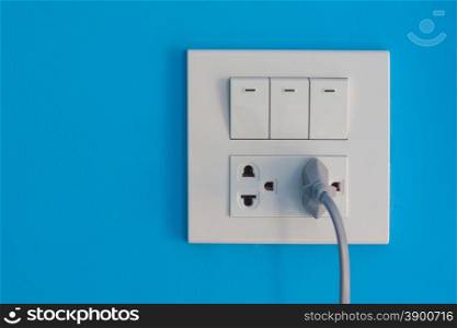 White electric outlet and switch mounted on painted blue cement wall