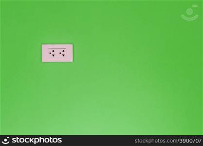 White electric outlet mounted on painted green cement wall
