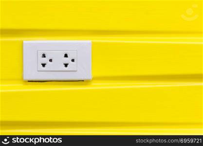 White electric plugs on modern yellow wallpaper.. White electric plugs on modern yellow wallpaper, with copy space background.