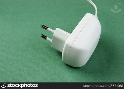 white electrical cable with plug on the green background