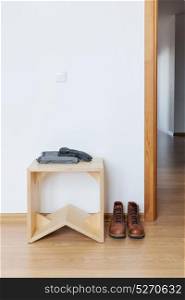 White empty anteroom with wooden stool and leather boots