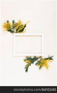 White empty frame with copy space surrounded by mimosa flowers. Mockup for a holiday card