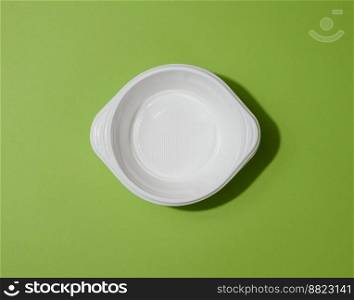White empty plastic soup bowl on green background, top view
