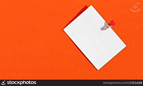 White envelope on a bright orange background, a letter with a heart for congratulations, for a wedding or Valentine?s Day. Photo with copy space
