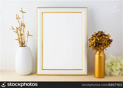 White fame mockup with white and golden vases. White frame mockup with white and golden vases. Portrait or poster white frame mockup. Empty white frame mockup for design presentation.