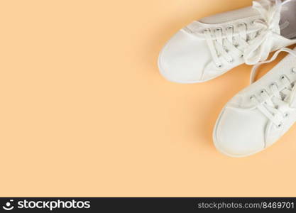 White female sneakers on coral background with copy space. top view, flat lay. Fashion mockup. White sneakers on coral background. copy space.