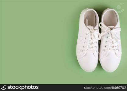 White female sneakers on green background with copy space. top view, flat lay. Fashion mockup. White sneakers on green background. copy space.