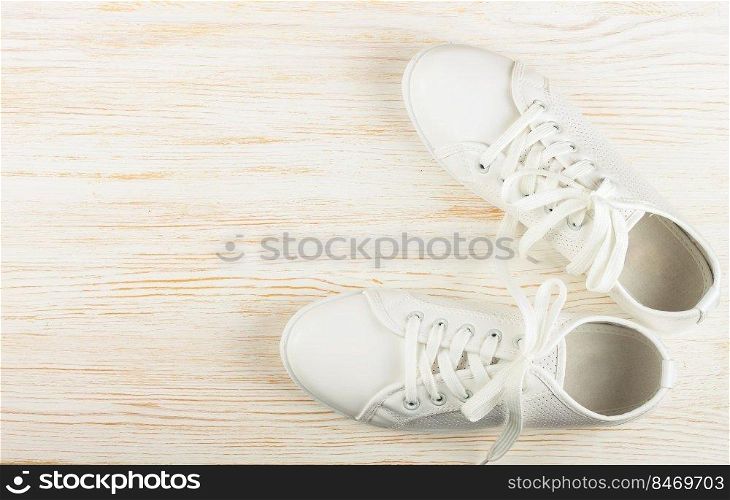 White female sneakers on white wooden background with copy space. top view, flat lay.. White sneakers on white wooden background. copy space.