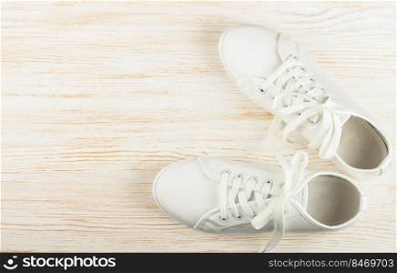 White female sneakers on white wooden background with copy space. top view, flat lay.. White sneakers on white wooden background. copy space.
