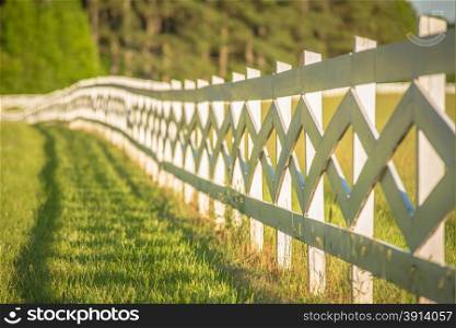 white fence leading up to a big red barn