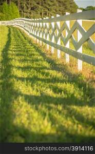 white fence leading up to a big red barn