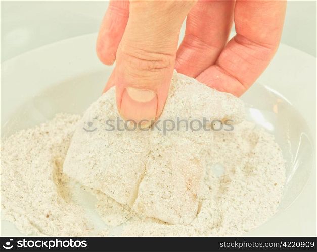 White fish seasoning. Person adding seasoning to a white fish fillet