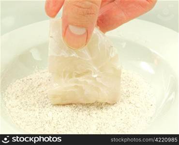 White fish seasoning. Person adding seasoning to a white fish fillet