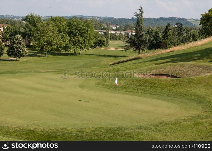 White Flagstick in Green Golf Course in Sunny Day.. White Flagstick in Green Golf Course in Sunny Day