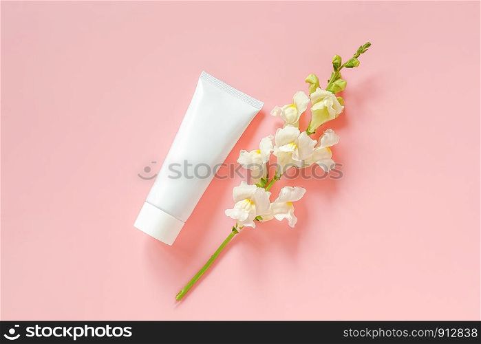 White flowers and cosmetic, medical white tube for cream, ointment, toothpaste or other product on pink background. Concept natural organic cosmetics, homeopathic cosmetology Mockup Top view.. White flowers and cosmetic, medical white tube for cream, ointment, toothpaste or other product on pink background. Concept natural organic cosmetics, homeopathic cosmetology Mockup Top view