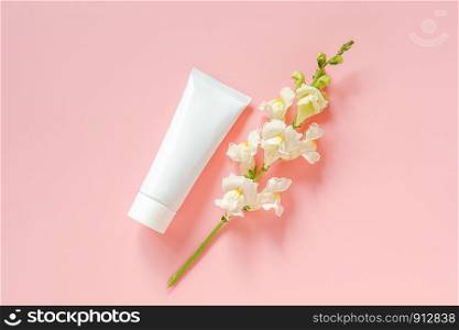 White flowers and cosmetic, medical white tube for cream, ointment, toothpaste or other product on pink background. Concept natural organic cosmetics, homeopathic cosmetology Mockup Top view.. White flowers and cosmetic, medical white tube for cream, ointment, toothpaste or other product on pink background. Concept natural organic cosmetics, homeopathic cosmetology Mockup Top view