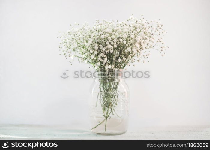White flowers in a vase on a wooden desk. White flowers in a vase