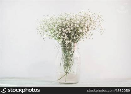 White flowers in a vase on a wooden desk. White flowers in a vase