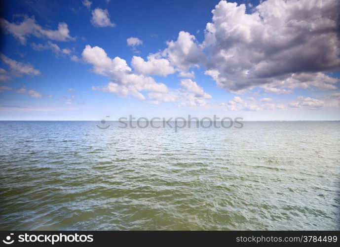 White fluffy clouds blue sky above a surface of the sea