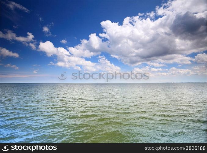 White fluffy clouds blue sky above a surface of the sea