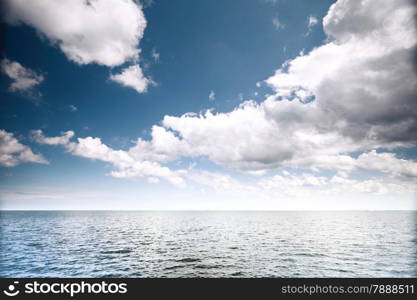 White fluffy clouds blue sky above a surface of the sea