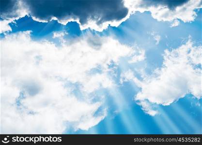 White fluffy clouds on the blue sky with sun rays. Nature background