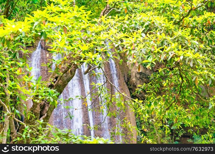White foamy streams of waterfall flowing down from cascade in green tropical jungle forest. Erawan National park, Thailand