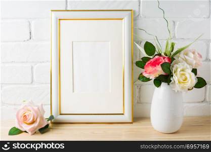 White frame mockup on brick wall with roses . White frame mockup on brick wall with roses. Vertical white frame mockup for portrait or poster. Empty white frame mockup for design presentation.