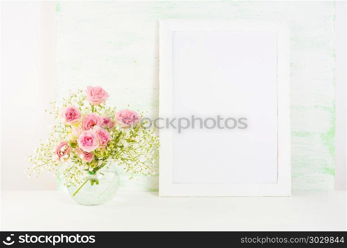 White frame mockup with pink rose flowers. White frame mockup with blooming pink roses. Empty frame mock up for presentation artwork. Template framing for modern art.