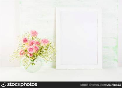 White frame mockup with pink rose flowers. White frame mockup with blooming pink roses. Empty frame mock up for presentation artwork. Template framing for modern art.