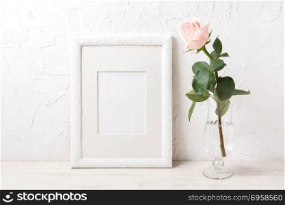 White frame mockup with rose in exquisite glass vase. White frame mockup with rose in exquisite glass vase. Empty frame mock up for presentation artwork.