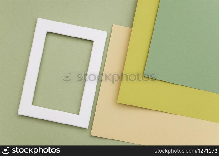 White frame on geometric green shades paper background. Copy space, mockup for your design, text.. White frame on geometric green shades paper background. Copy space, mockup for your design, text