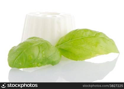 White fresh cheese with fresh basil leaves on white reflective background.