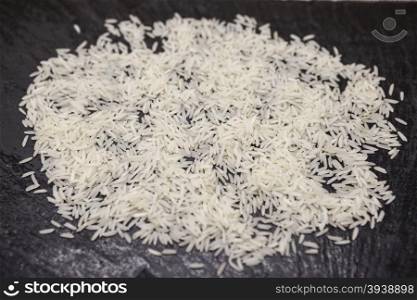 White friable crude Thai rice on a stone black background.. White friable crude Thai rice on a stone black background