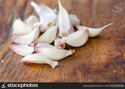White garlic cloves on wooden cutting board in the kitchen.