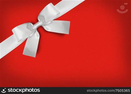 White gift bow on red background copy space for text. White gift bow on red