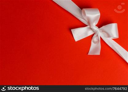 White gift bow on red background holiday gift concept. White gift bow on red