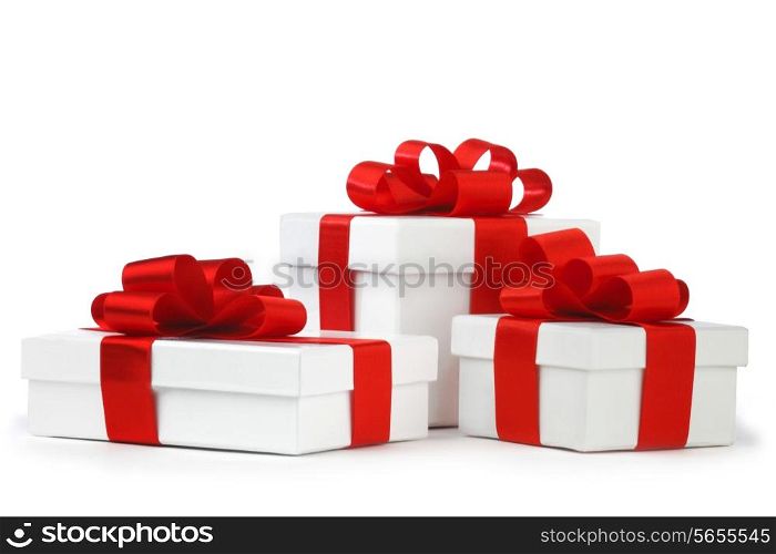 White gift boxes with red ribbon bows isolated on white background close-up