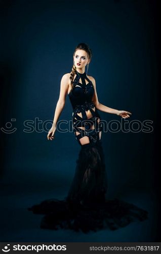 white girl modell on a dark background in a dress made of cut stripes of black fabric