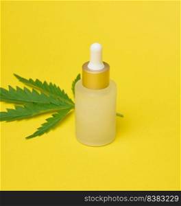 White glass bottle with pipette and green cannabis leaf on yellow background