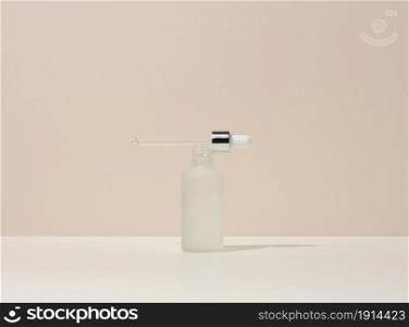 white glass bottle with pipette stands on a beige background. Cosmetics SPA branding. Packaging for gel, serum, advertising and product promotion, mock up