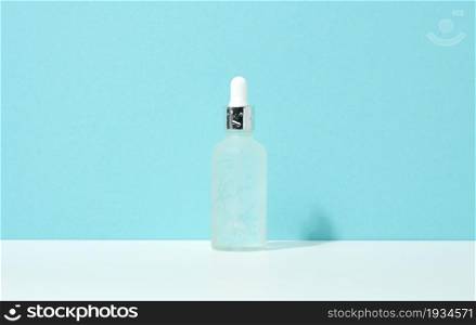 white glass bottle with pipette stands on a blue background. Cosmetics SPA branding. Packaging for gel, serum, advertising and product promotion, mock up